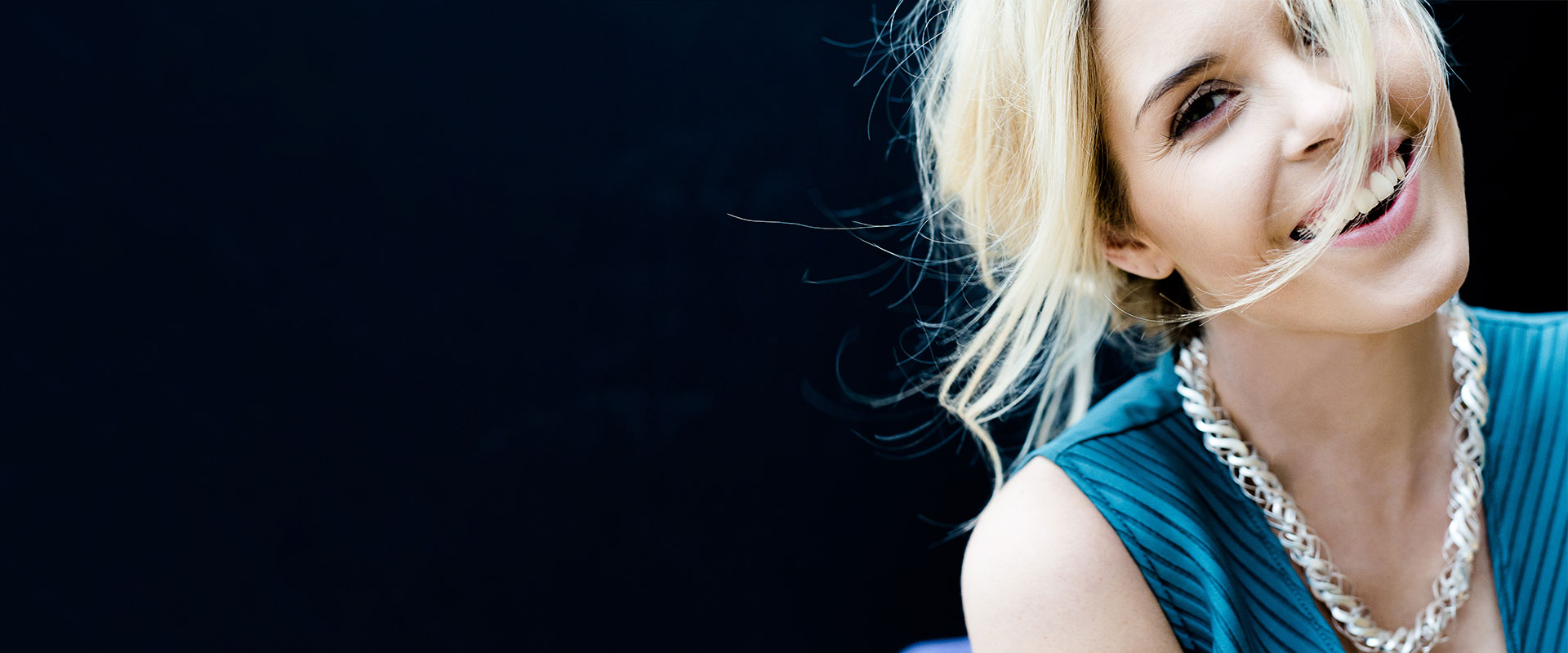 Lachende Frau mit blonden, wehenden Haaren
